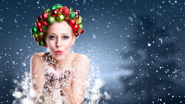 Weihnachtlich geschmückte Frau pustet Schnee