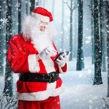 Weihnachtsmann checkt Tablet vor winterlichem Hintergrund
