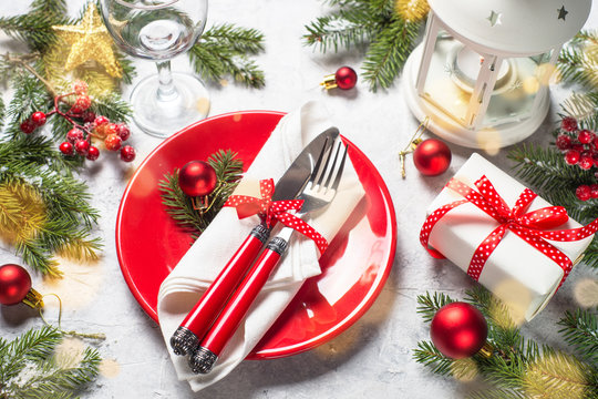 Christmas table setting. Plate, silverware, present and decorations.