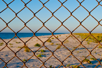 a large grid of metal fences a deserted beach wire fence pass forbidden yellow sand blue sea shore clean blue sky summer warmth