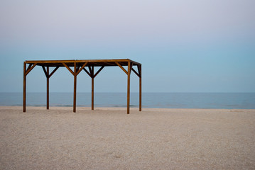 high wooden canopy awning arbor deserted beach early in the morning shore of the sea calm blue clear sky weekend rest Dawn