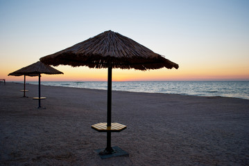 large beach umbrella made of straw and metal stands on the beach blue sea blue sky summer morning evening calm