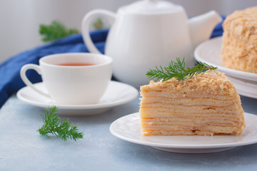 Round multi-layered cake Napoleon with custard, on a light-blue table background. Selective focus. Russian cuisine.