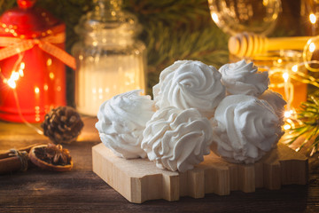 Homemade zephyr or marshmallows with pine-tree branches, cones, spices, Christmas atmosphere, wooden background