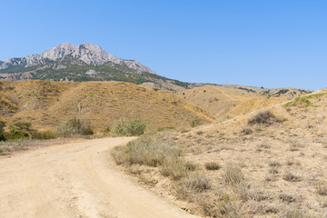 Steppe landscape with views of the rocky mountains and the road turning at an unknown distance, the Crimea, Fox Bay reserve