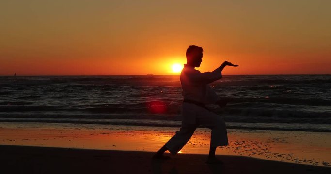 Silhouetted karate kata on the beach by a teenager