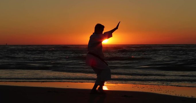 Silhouetted karate kata on the beach by a teenager