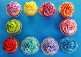 Frame made of tasty cupcakes on color background