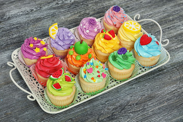 Vintage tray with beautiful cupcakes on wooden background