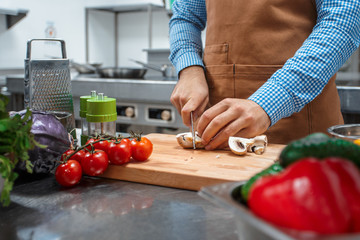 The chef in brown apron cooking in a restaurant kitchen