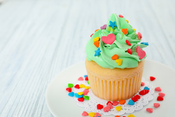 Plate with beautiful cupcake on wooden table