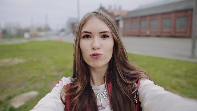 Happy hipster teen girl making selfie photo in urban background