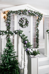 house entrance decorated for holidays. Christmas decoration. garland of fir tree branches and lights on the railing