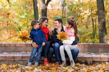 Fototapeta premium A happy family having fun in the park in autumn walking and hugging. Family, love, happiness concept. Family of four with mother father sister and a little cute brother