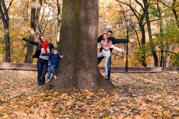 A happy family having fun in the park in autumn walking and hugging. Family, love, happiness concept. Family of four with mother father sister and a little cute brother