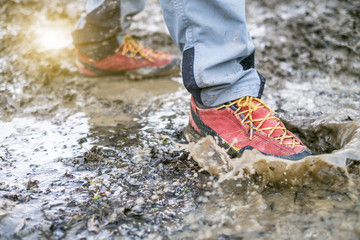 Detail of trekking boots in a mud. Muddy hiking boots and splash of water. Man splashing in muddy and water in the countryside. - 181988718