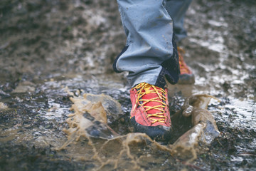 Detail of trekking boots in a mud. Muddy hiking boots and splash of water. Man splashing in muddy...
