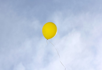Yellow balloon flying on a blue sky background