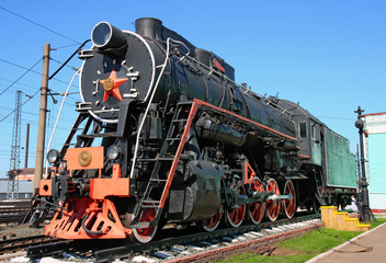 Fototapeta na wymiar Old black locomotive in the railway depot in the parking lot