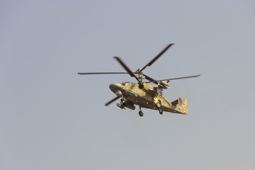 Fototapeta na wymiar Green helicopter flies against the blue sky