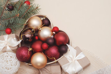 Winter or Cristmas Decorations Background - Red Balls Mistletoe and Green Fir Branches, gift Boxes on Warm Ivory Background with Copy Space