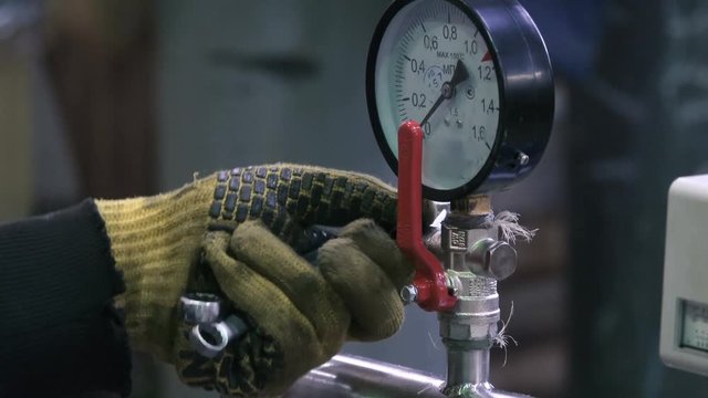Worker's hand that installs the pressure gauge on the water pump in the factory. Close up shot. Blurred background
