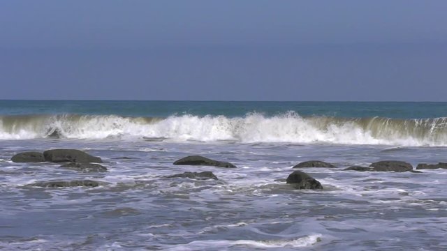 Slow motion of waves with rocks on the foreground in Manora, Peru