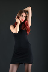  girl with long red and shiny wavy hair . Beautiful model with curly hairstyle .