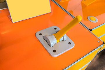 Closed up toggle controller with yellow handle on grey panel of orange box.