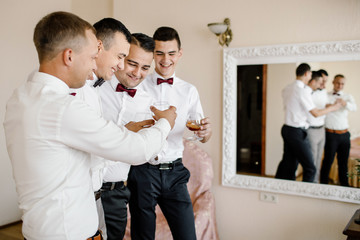 Handsome groom preparing for wedding ceremony in hotel room
