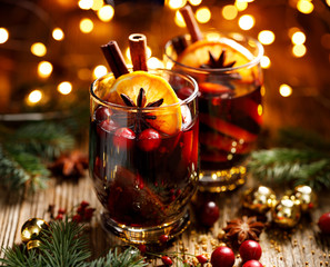 Christmas mulled red wine with spices and fruits on a wooden rustic table. Traditional hot drink at...
