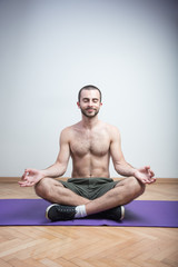 Young caucasian man practicing yoga shirtless, enjoying his quiet time to relax and meditate