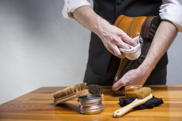 Footwear Concepts and Ideas. Closeup of Hands of Man Cleaning Premium Derby Boots With Variety of Brushes