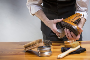 Footwear Concepts and Ideas. Closeup of Hands of Man Cleaning Premium Derby Boots With Variety of Brushes and Accessories.