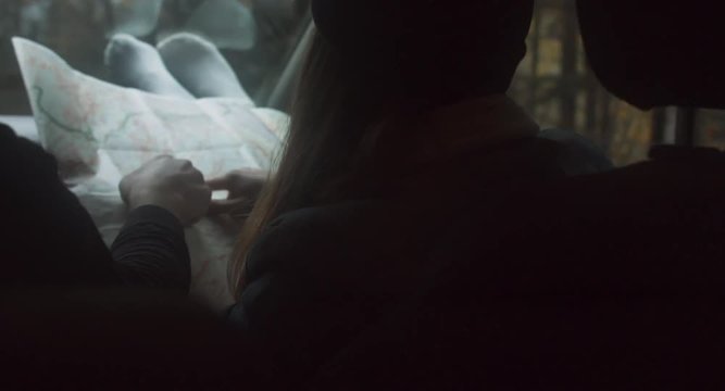Rear view shot of couple traveling by car. Woman holding map, searching for the right way. Couple on a road trip. 4K UHD