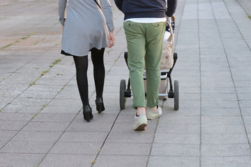 parents with a child in a stroller walk along the street