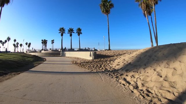 Slow motion moving shot on bike path near the Venice Beach skateboard park in Los Angeles California.