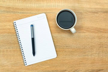 A cup of coffee with note and pen on working table with copy space top view.