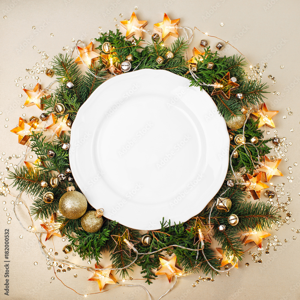 Wall mural plates with gold cutlery on christmas decoration background. flat lay, top view.