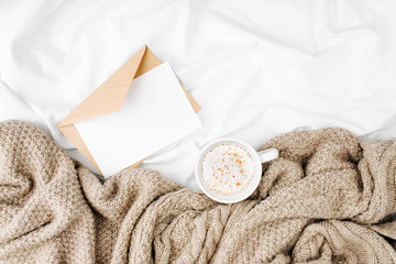 Mockup card and Cup of coffee on bed with warm plaid. Copy space. Flat lay, top view