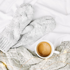 Cup of coffee on bed with warm plaid. Copy space. Flat lay, top view