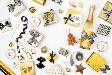 Flat Lay Christmas or Party Background with Gift boxs, Champagne bottle, Bows, Decorations and Wrapping Paper in Gold and Black colors. Flat lay, top view