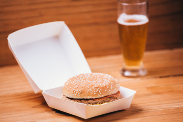 Fresh and juicy hamburger and beer on wooden background