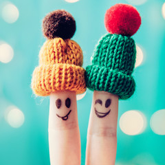 Family winter vacation. Couple of  finger on knitted hats smiling and wink. Togetherness concept