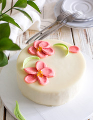 Mousse carrot orange cake with chocolate flowers on a wooden light background. Summer Flowers