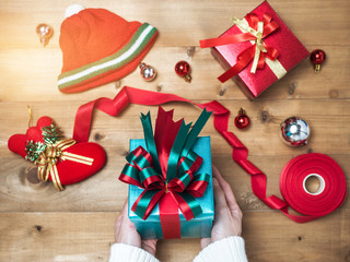 Creative hobby. Woman's hands wrap christmas holiday handmade present in craft paper with twine ribbon. Making bow gift box, decorated with cute object on wooden table, top view.flat lay composition