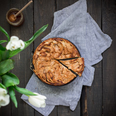 Homemade cake with whole wheat flour with apples on a wooden background. Food photo with hands and...