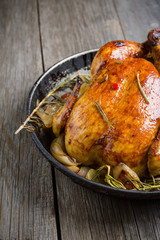 Roasted chicken in pan on the rustic wooden background. Selective focus.