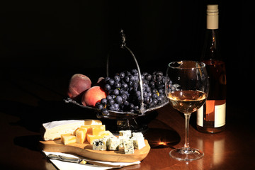 Cheese, wine and fruit on a dark background