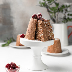 Chocolate mini raw cake with cherry and cottage cheese, decorated with cherries and coconut. Traditional Russian Easter dessert. On a light white wooden background. Piece of cake.